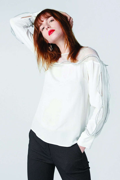 White long-sleeve blouse with ruffled shoulder detail and sheer layered sleeves