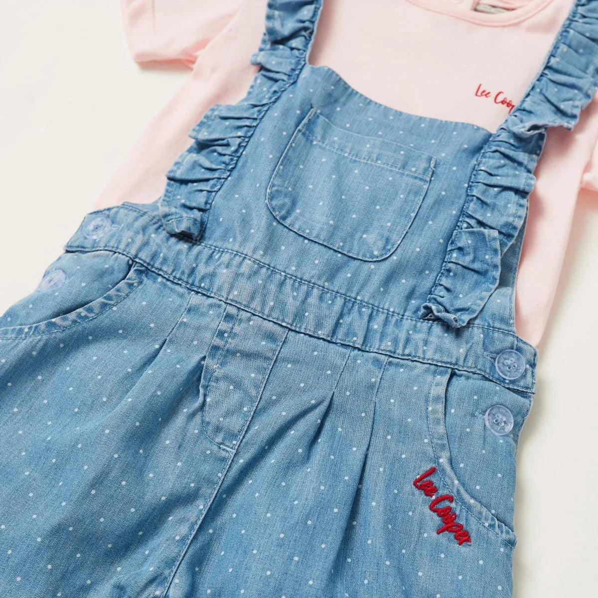 Blue denim-style baby overalls with adjustable straps and red logo patch
