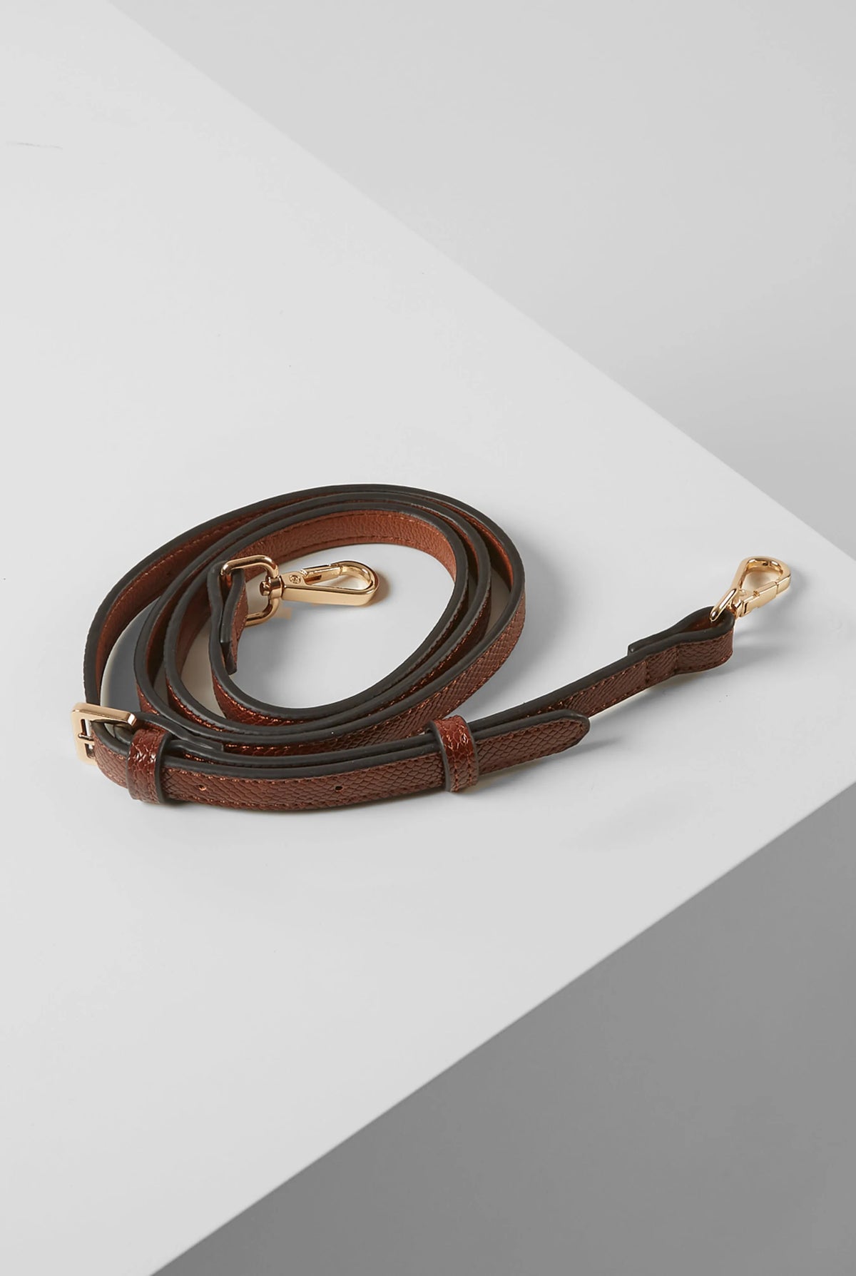 Brown leather crossbody strap with gold clasp and lobster hardware