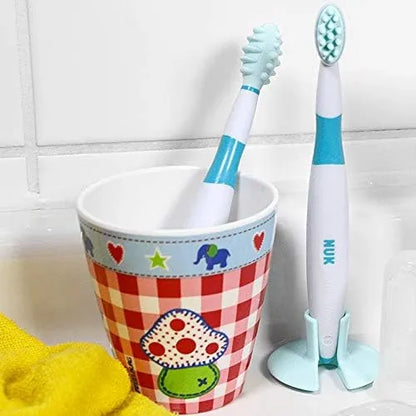 Kids toothbrushes in a cup: mint bristle heads and white handles with teal grip