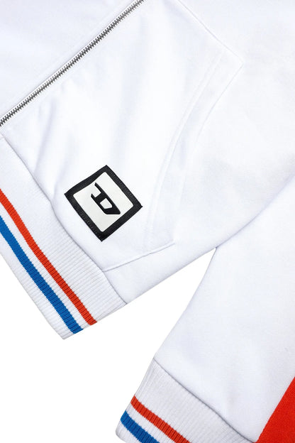 White hoodie sleeve with black logo patch and orange, blue striped rib trim