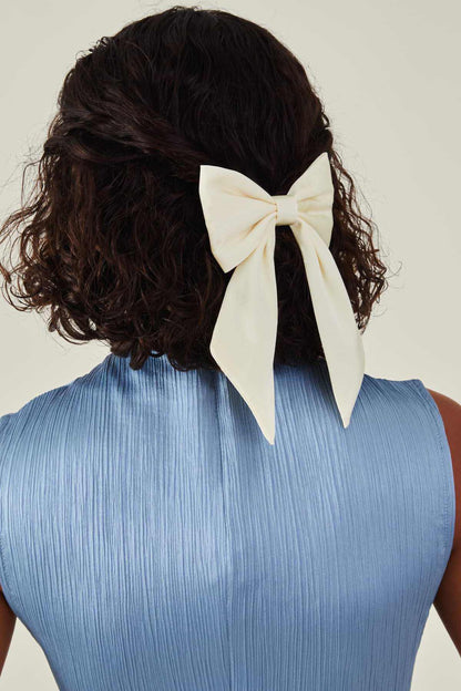 Cream bow hair accessory worn on dark curly hair