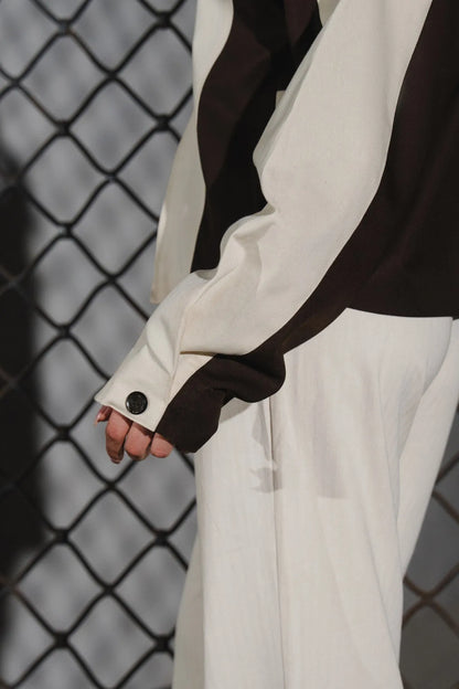Beige jacket sleeve and cuff with dark brown panel, buttoned cuff detail