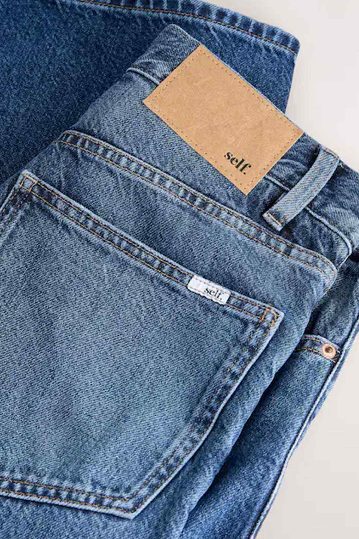 Dark blue denim jeans back pocket close-up with tan logo patch