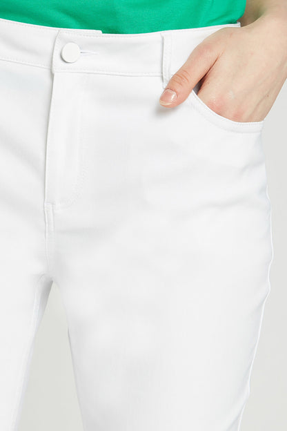 Close-up of white pants waistband with button detail and front pocket
