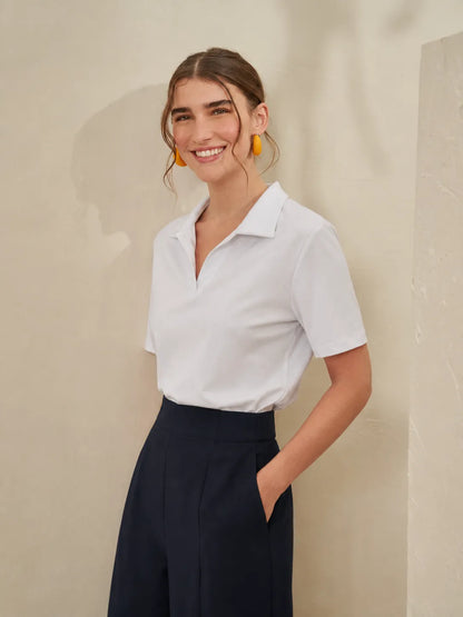 White short-sleeve blouse with pointed collar and open neckline; dark wide-leg trousers