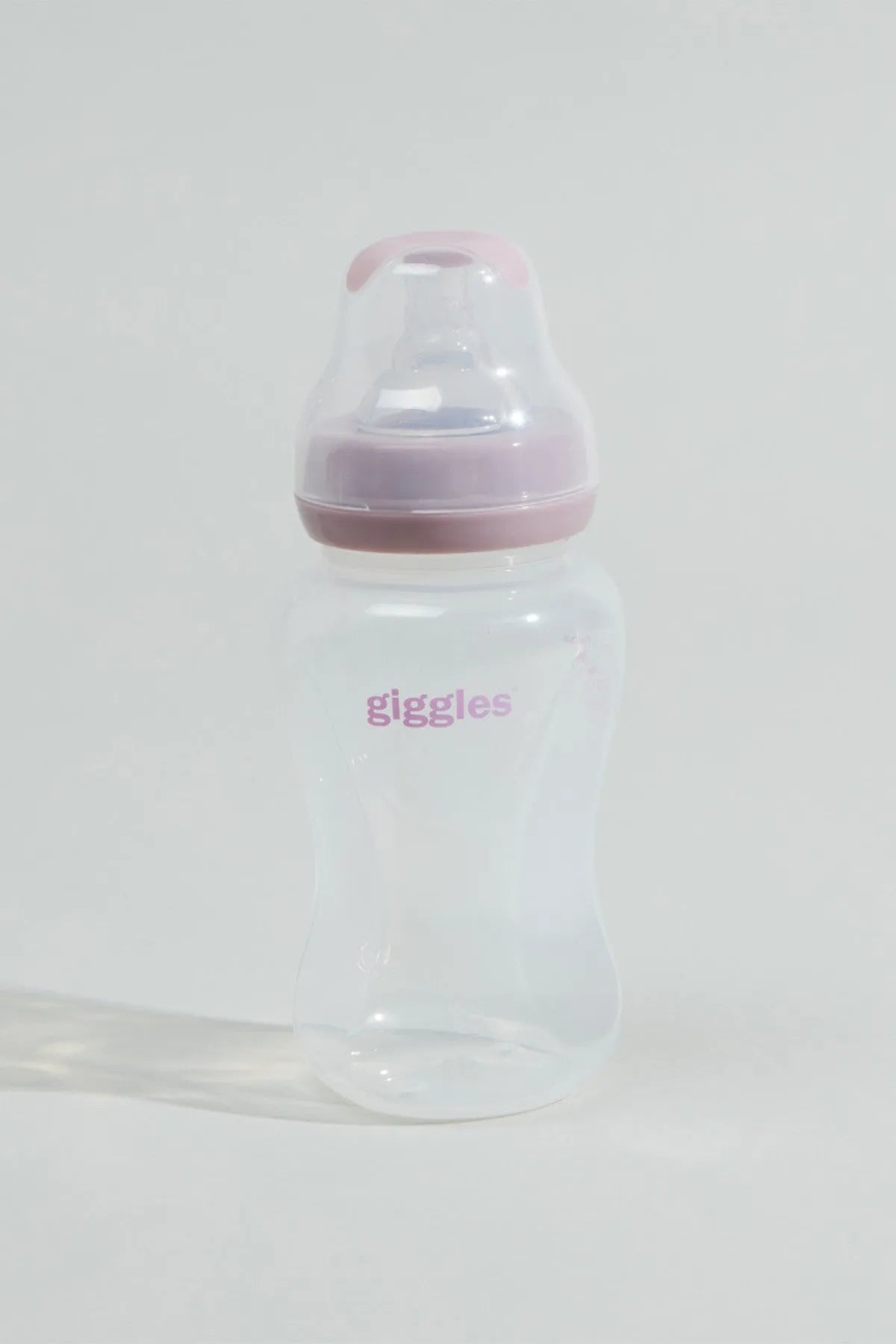 Clear baby bottle with pink lid and 'giggles' print, standing upright