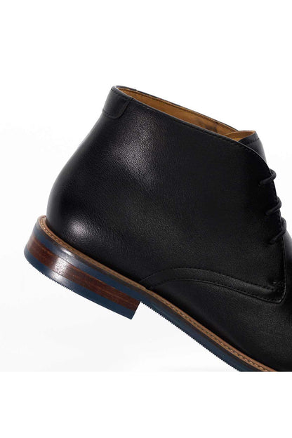 Black leather ankle boot close-up: lace-up upper, stitched welt, low sole