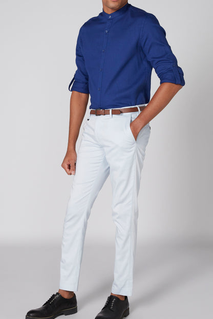 Men's blue button-up shirt with rolled sleeves and light trousers with belt