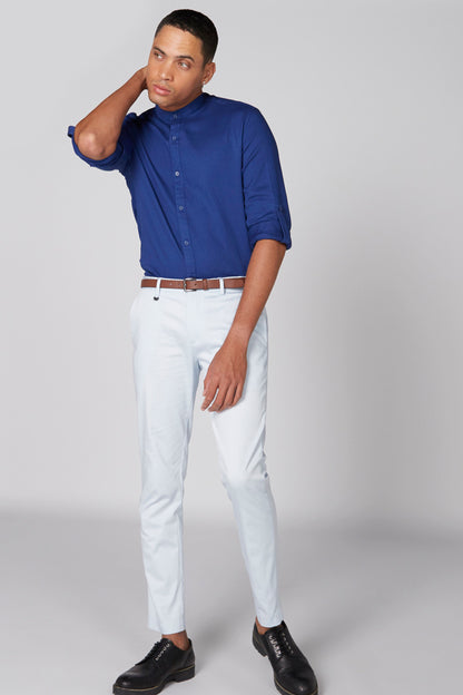 Men's blue button-up shirt and light trousers with belt, standing pose