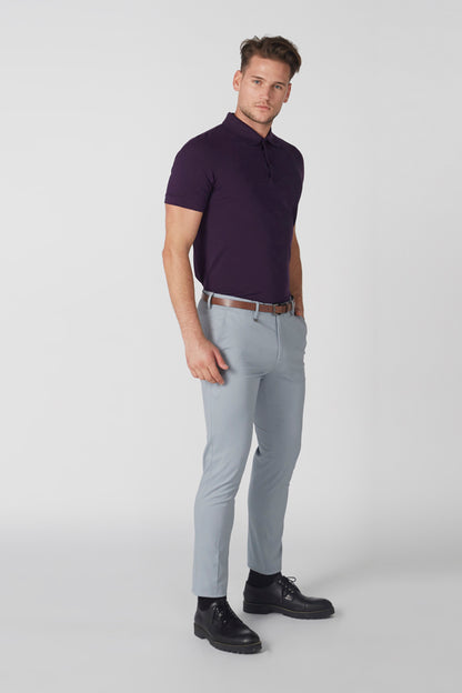 Men's purple polo shirt and light blue trousers with brown belt, front view
