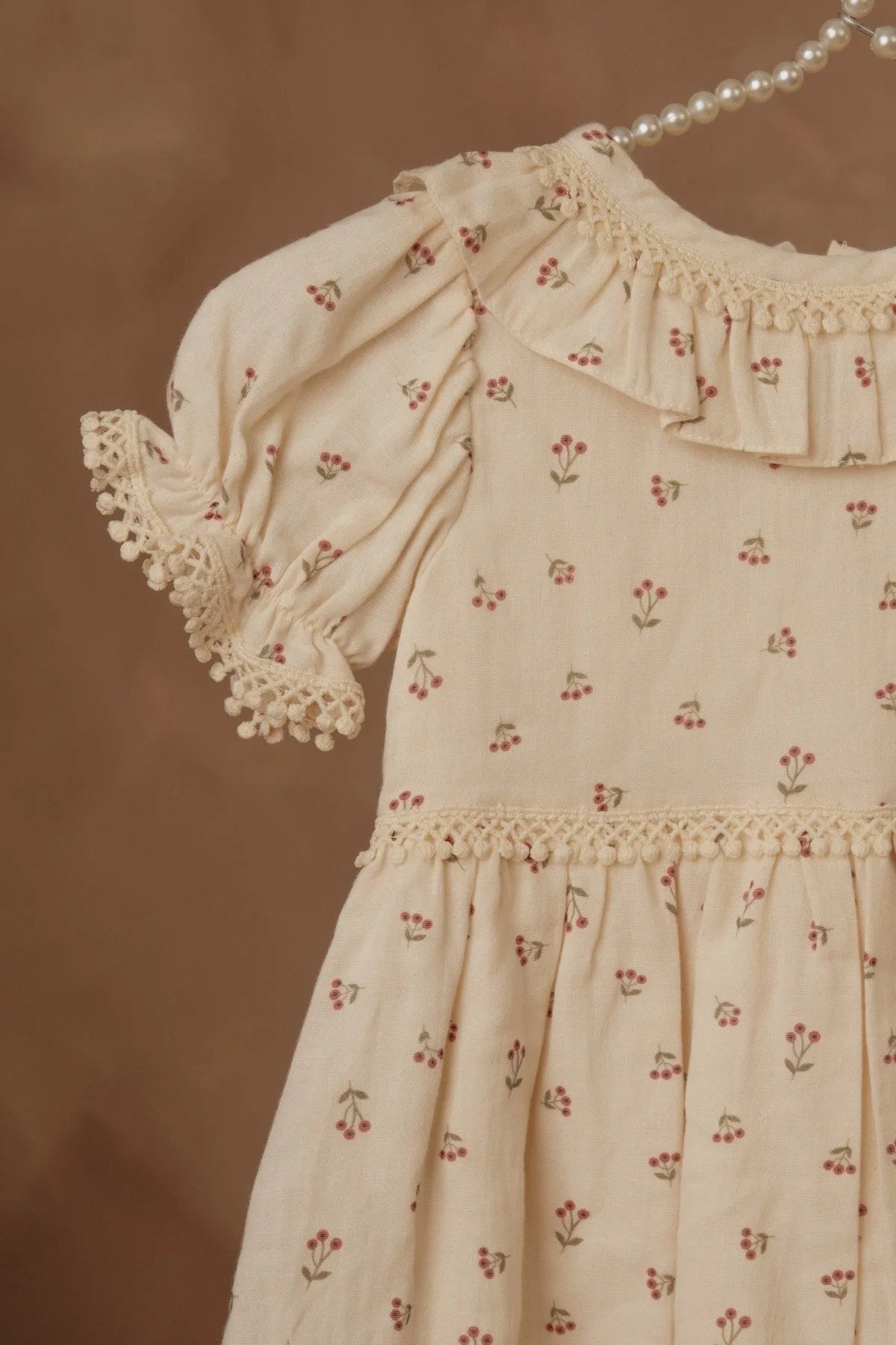 Cream floral dress close-up with ruffled neckline, gathered sleeves, button front