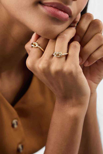 Gold twisted rings with small clear stones, worn on finger