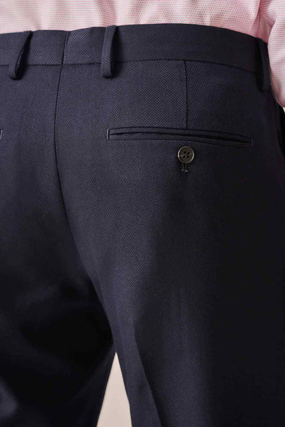 Navy trouser front with pleat, pocket flap, and button fastener at waistband.
