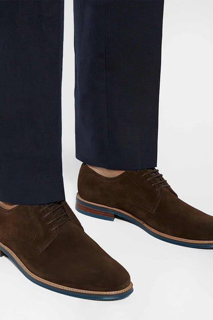 Brown suede lace-up shoes with blue-and-orange sole trim, worn with navy trousers