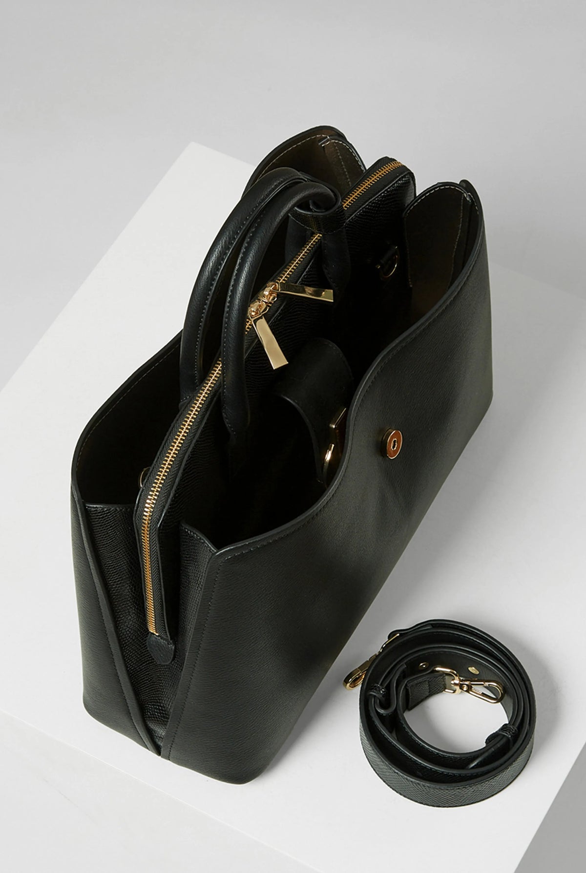 Black handbag with front lock detail and zip pocket; includes matching crossbody strap