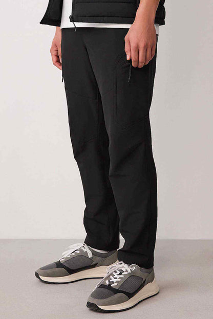 Black straight-leg trousers with white sneakers, worn with quilted puffer gilet