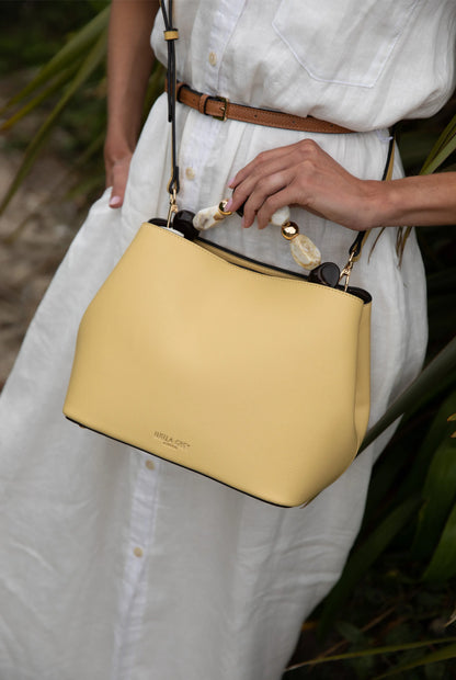 Yellow hobo handbag close-up with tortoiseshell beaded handle and gold-tone hardware