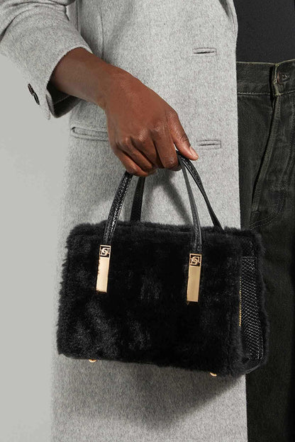 Dune London black faux-fur handbag held by hand, with short handles and shoulder strap