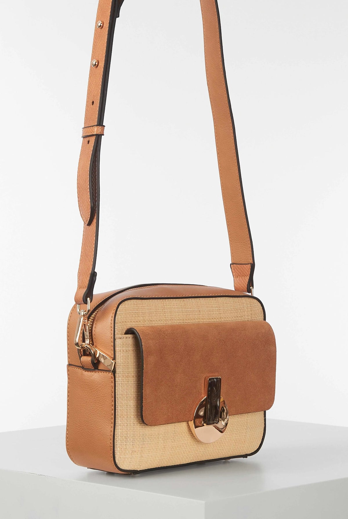 Brown crossbody bag on adjustable shoulder strap, front flap with clasp