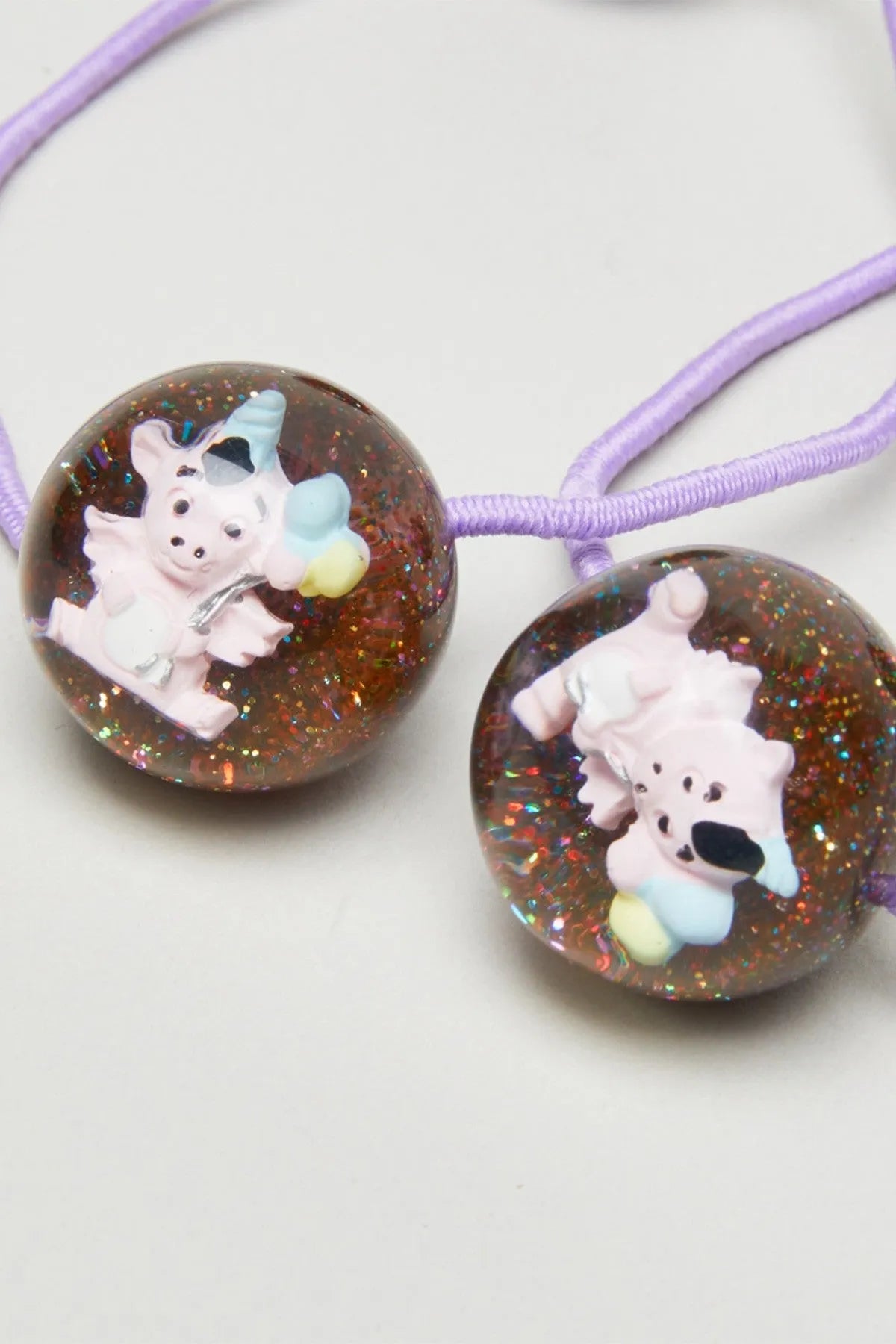 Pair of glittery brown bead charms with cartoon baby animal on purple elastic