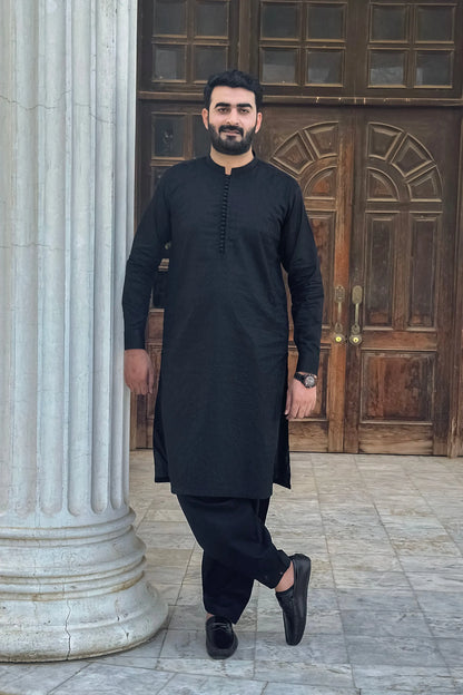 Men's black kurta with matching shalwar trousers and slip-on shoes