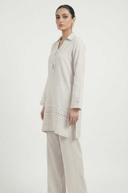 Light grey tunic with embroidered neckline and lace hem, paired with trousers.