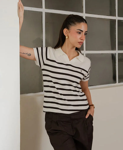 Fitted striped polo shirt with black-and-white stripes, collared neckline, arm-raised side view