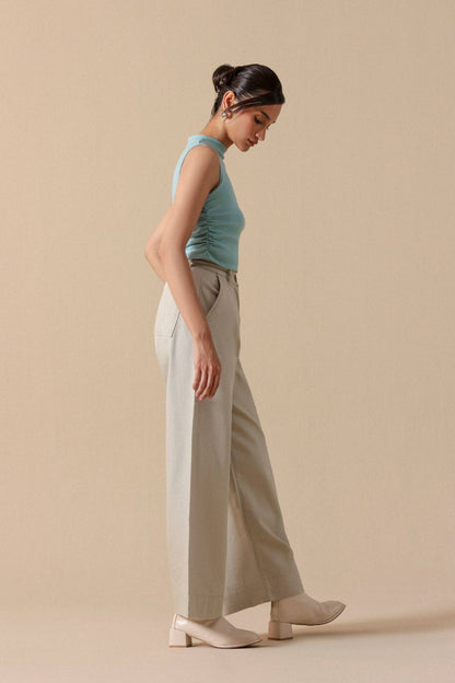 Mint sleeveless crop top with light beige wide-leg trousers, side profile