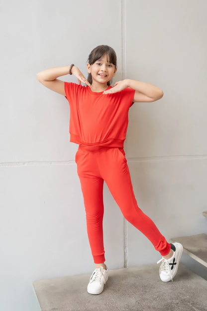 Kids red short-sleeve top and jogger pants set, standing with hands behind head