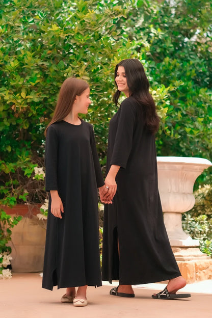 Black long-sleeve maxi dress with round neck and side slit, full length