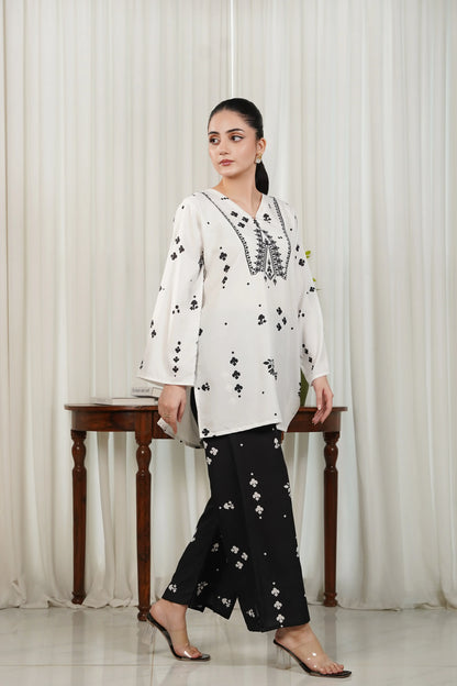 White printed V-neck kurta with black trim and black motif trousers, side view