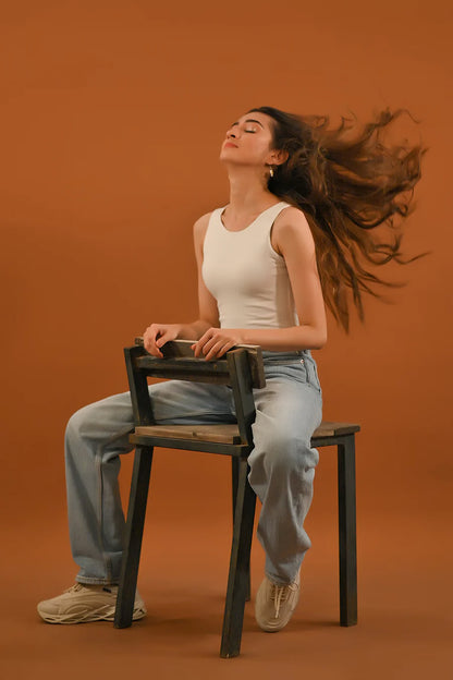 White sleeveless crew-neck tank top worn by seated model