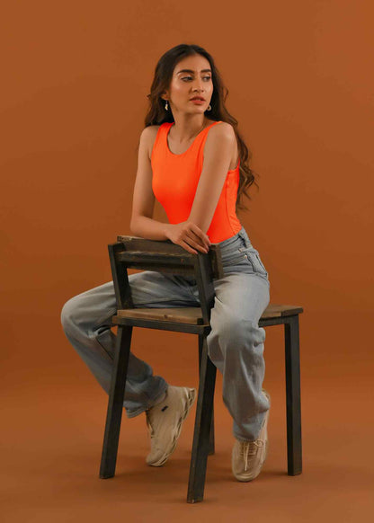 Thread orange sleeveless tank top with light-wash straight jeans, seated view