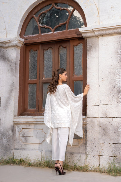 White embroidered kurta with cape overlay sleeves and white cropped pants, side view