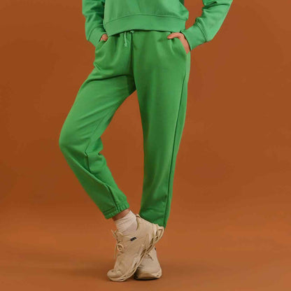 Green jogger pants with elastic cuffs and drawstring waist, styled with matching sweatshirt