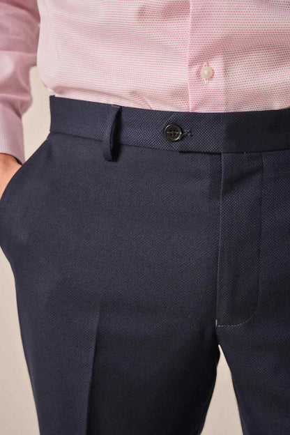 Navy trousers waistband with belt loops and dark button detail.