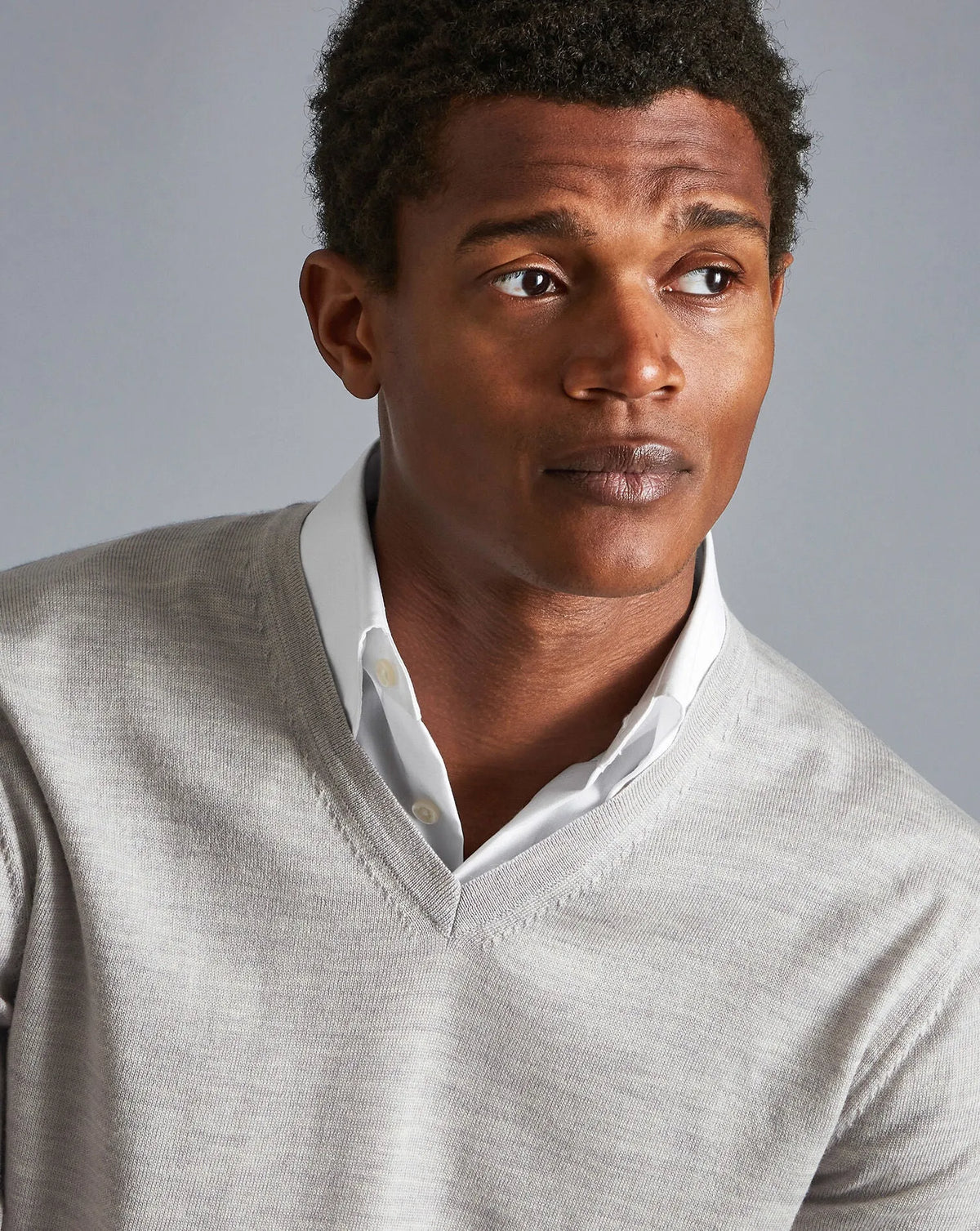 Men's grey V-neck knit sweater with ribbed neckline and white shirt underneath