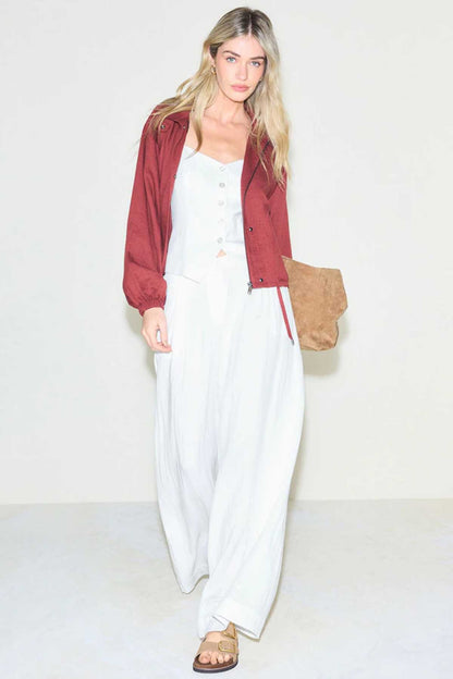 White wide-leg trousers with drawstring waist, worn under burgundy button jacket