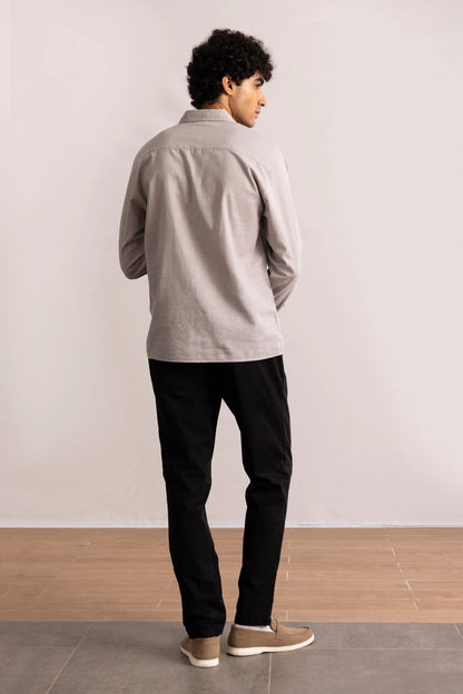 Grey button-up shirt on model from back, long sleeves, untucked hem