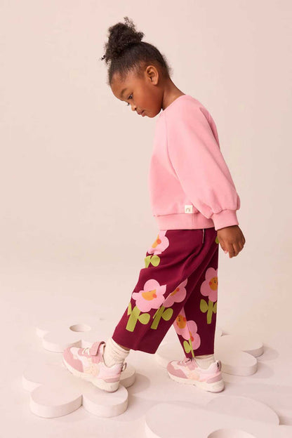 Kids burgundy floral pants with elastic waistband, full-body side view