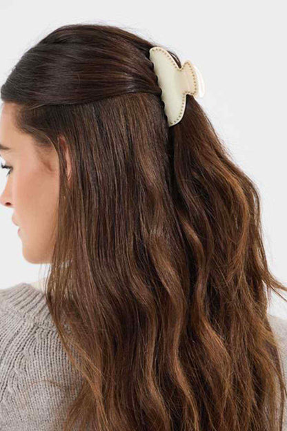 Cream hair claw clip with scalloped edges, holding hair half-up