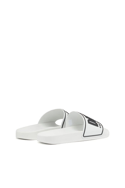 White slide sandals with black logo patch on the front strap