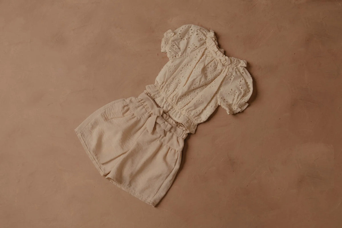 Cream shorts with elastic waist and front bow, gathered at the sides