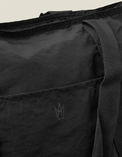 Close-up of black travel tote fabric with subtle logo embossing on panel
