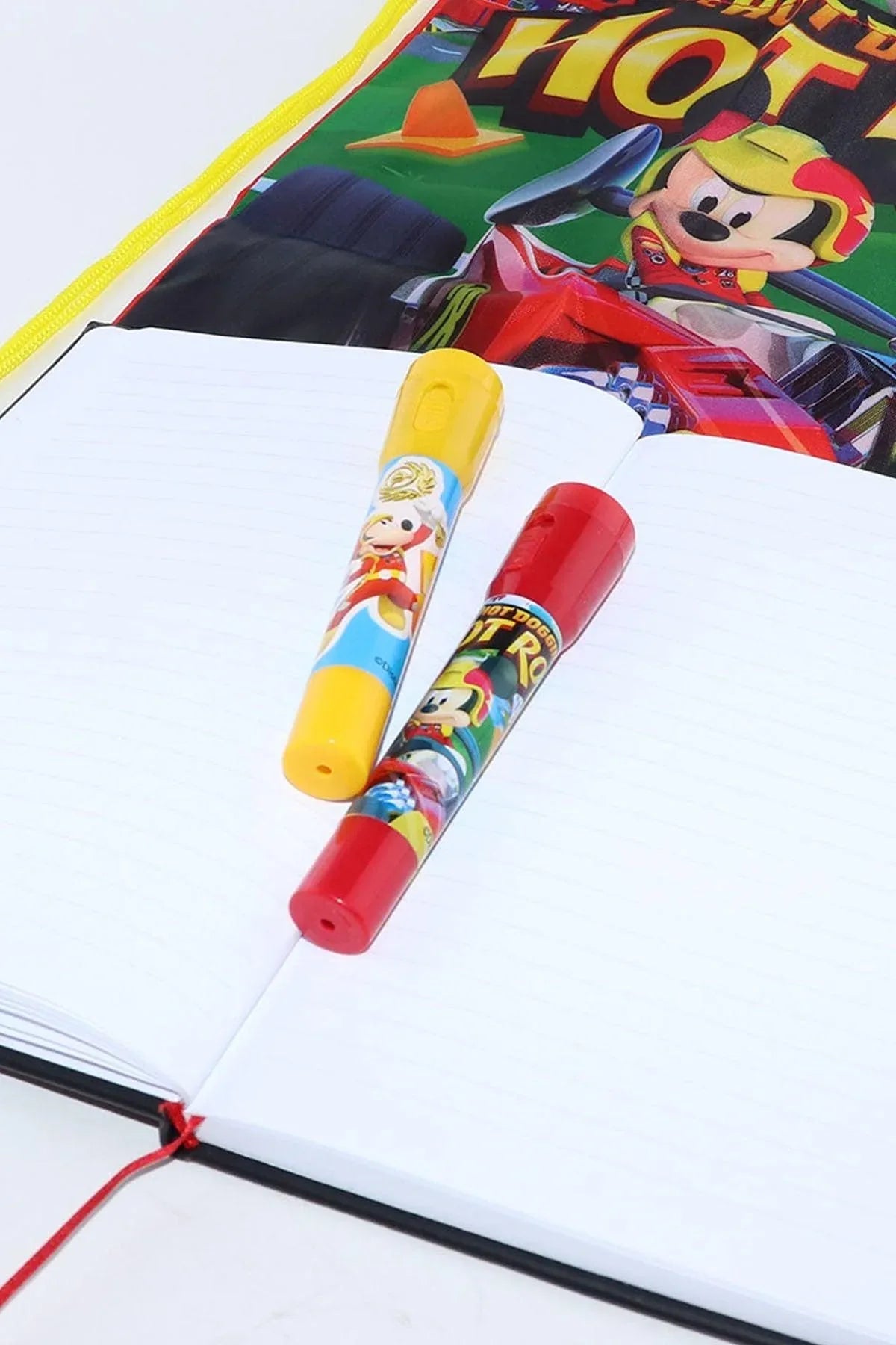 Disney character crayons, yellow and red, on white fabric near an edge