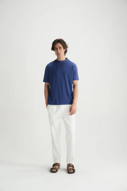 Blue crew-neck short-sleeve T-shirt with white pants, standing front view