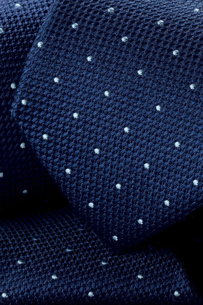 Blue knit necktie with small dot pattern texture close-up
