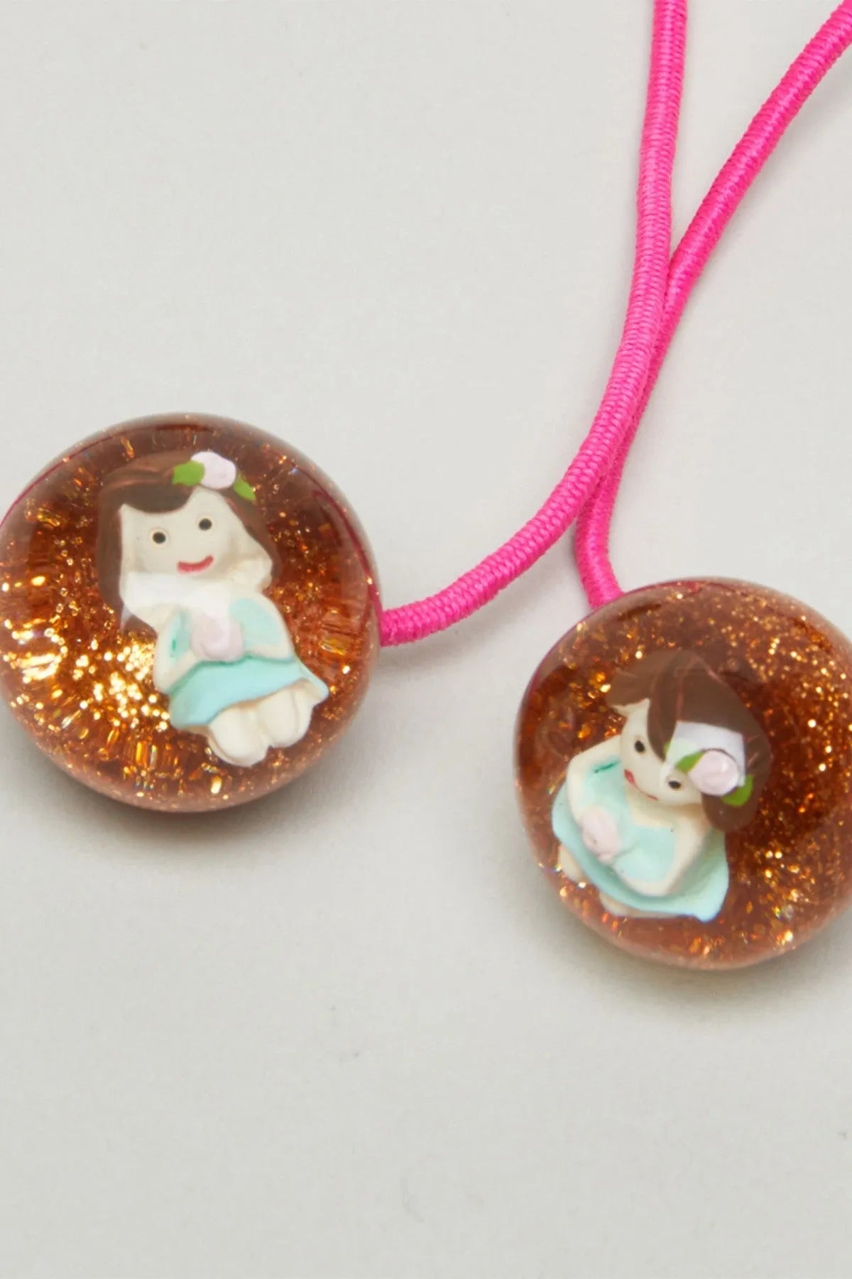 Pink elastic cords with brown glitter beads featuring cartoon baby faces