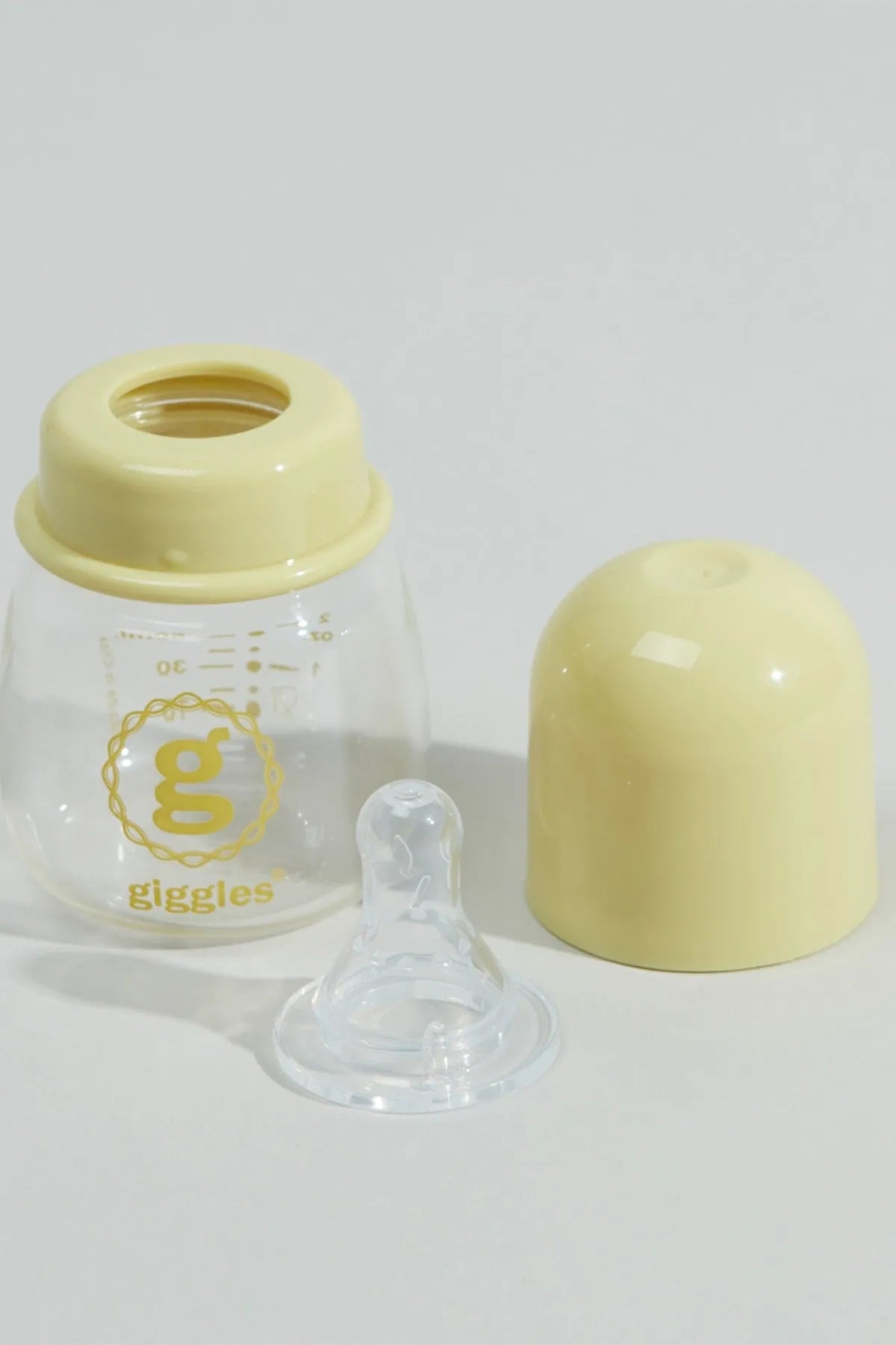 Baby bottle with yellow cap, clear body, and separate clear silicone nipple